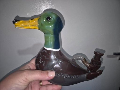 A hand-held ceramic duck figurine with a pipe attachment.
